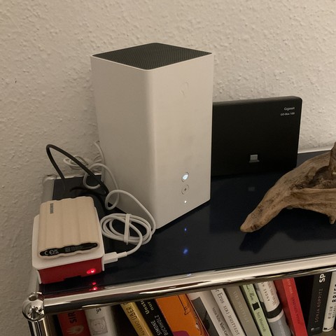 A photo of a red and white Raspberry Pi next to a Swisscom InternetBox router.