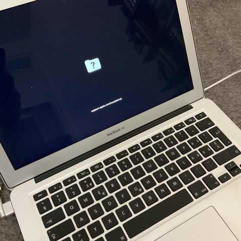 Photo of a MacBook Air displaying a folder symbol with a question mark.