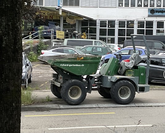 kleiner dunkelgrüner Kipper mit weisser Beschriftung richard-gartenbau.ch, parkiert am Strassenrand