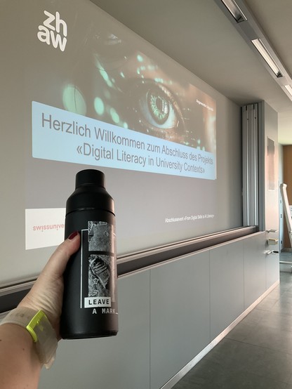 Photo of a ZHAW “Leave a Mark” bottle in front of the welcome slide for the event.