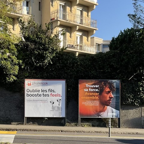 Two advertising boards on a street. On the left, one for wireless earbuds: “Oublie les fils, booste tes feels” (“Forget your wires, boost your feels”). On the right, for a health insurance: “Trouver sa force. Avancer ensemble” (“Finding one’s strength. Together ahead.”)