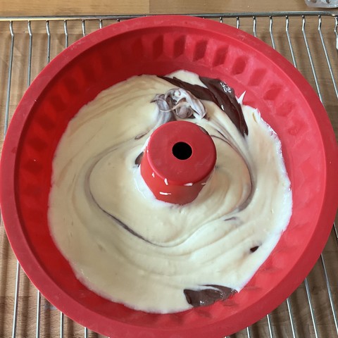Rote Silikongugelhupfform mit Marmorkuchenteig drin