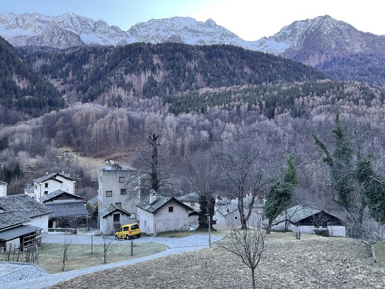 view from a window into the valley: all gray as there are no leaves, but clear view of mountains, trees, houses, sky