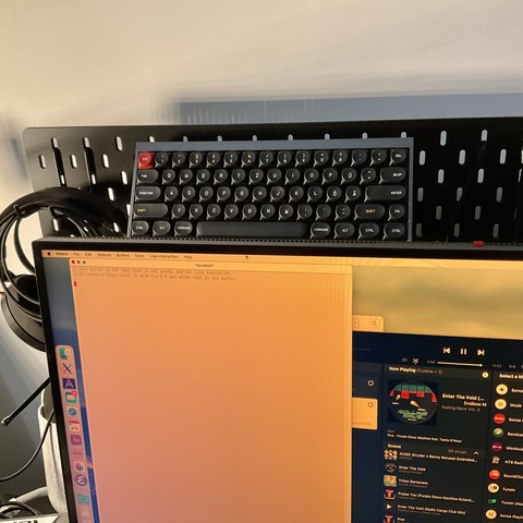 Photo of a keyboard on an Ikea Skådis board mounted behind a monitor.